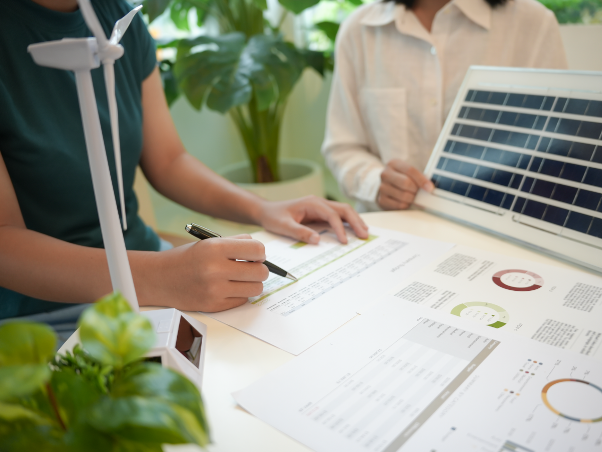 Menschen sitzen an einem Tisch, welcher mit Unterlagen zum Energieverbrauch ausgelegt ist